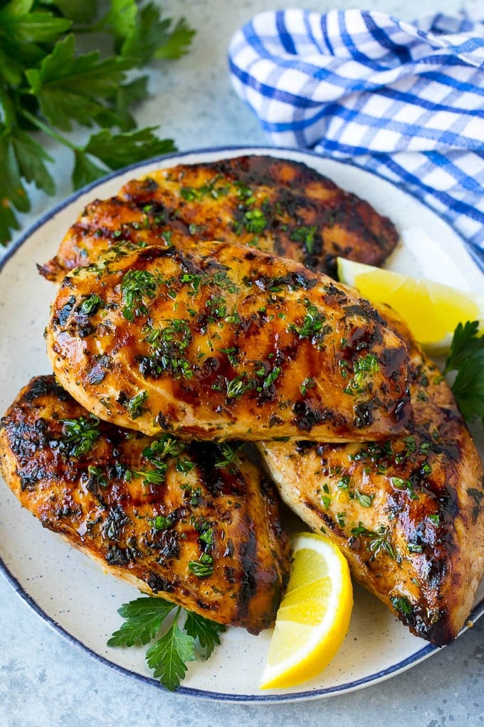 Grilled Chicken Breast Recipe | Marinated Chicken Breast | Chicken Marinade #chicken #grilling #marinade #summer #dinner #fuyos A platter of grilled chicken breast served with parsley and lemon.