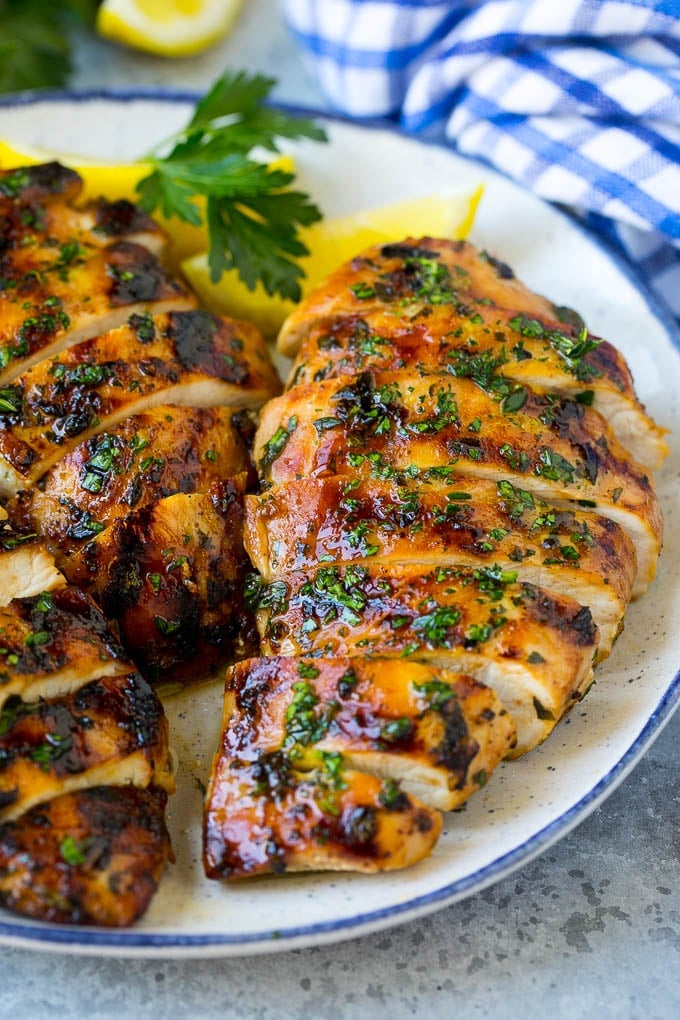 Grilled Chicken Breast Recipe | Marinated Chicken Breast | Chicken Marinade #chicken #grilling #marinade #summer #dinner #fuyos Sliced grilled chicken breast garnished with herbs and lemon.