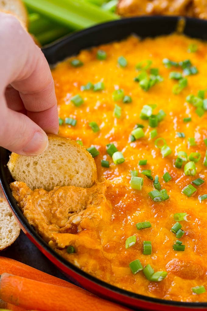 Buffalo Ranch Chicken Dip | Buffalo Chicken Dip | Baked Buffalo Dip | Cheesy Buffalo Dip #buffalowings #buffalochicken #dip #lowcarb #appetizer #fuyos Baked buffalo chicken dip with a baguette slice scooping some out.