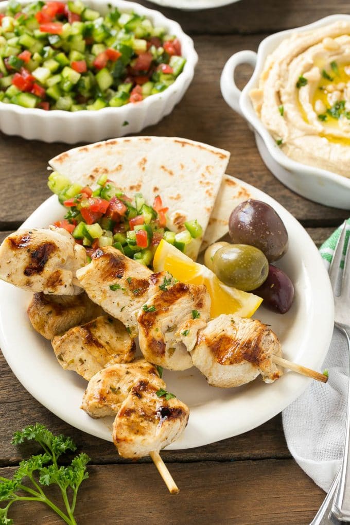Greek Chicken Souvlaki Recipe | Easy Greek Chicken | Chicken Souvlaki | Greek Chicken Skewers | Easy Greek Chicken Skewers #chicken #kabobs #glutenfree #keto #lowcarb #grilling #fuyos A plate of skewers with olives and pita bread.