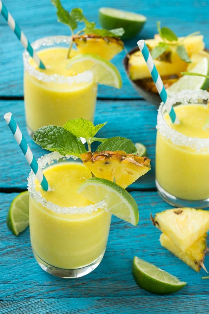 Pineapple Coconut Smoothie Recipe |Tropical Smoothie | Pineapple Smoothie #smoothie #pineapple #coconut #healthy #cleaneating #fuyos Glasses of pineapple coconut smoothie garnished with limes and mint.