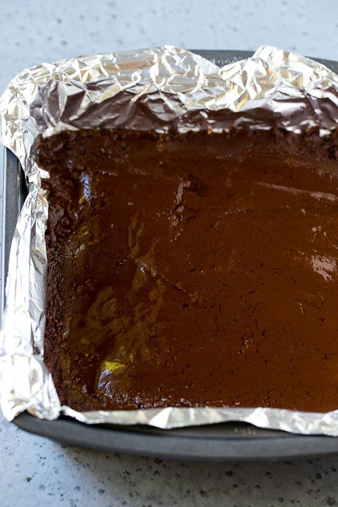 Chocolate Peanut Butter Fudge Recipe | Peanut Butter Cup Fudge | Easy Fudge Recipe #chocolate #peanutbutter #fudge #baking #dessert #fuyos A layer of chocolate fudge in a pan.