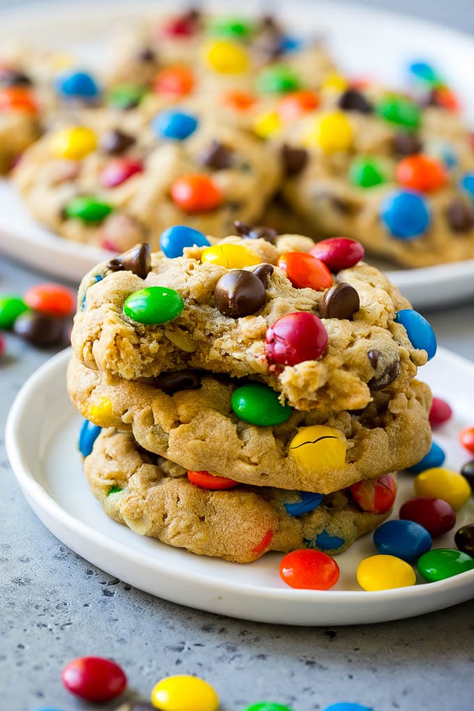 Monster Cookies Recipe | Oatmeal Cookies | Peanut Butter Cookies | M&M's Cookies #baking #cookies #dessert #peanutbutter #chocolate #fuyos A stack of monster cookies with a bite taken out of one.