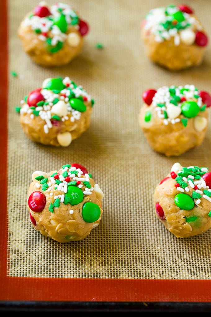 Christmas Monster Cookies Recipe | Oatmeal Cookies | Peanut Butter Cookies | M&M's Cookies #baking #cookies #dessert #peanutbutter #chocolate #fuyos #christmas #sprinkles Balls of cookie dough on a baking sheet.
