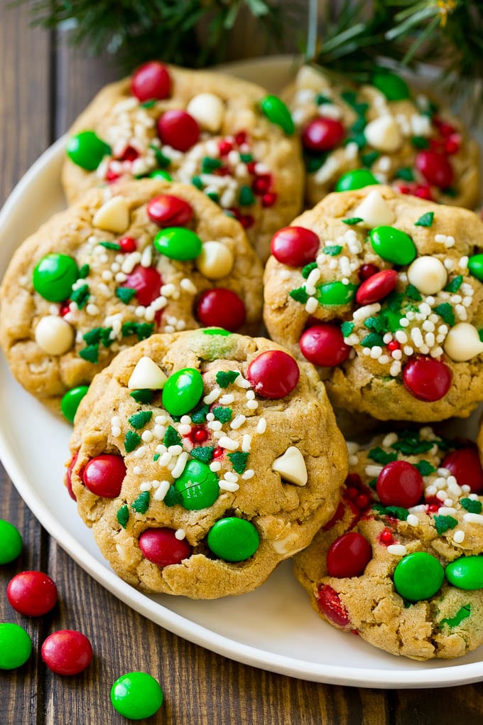 Christmas Monster Cookies Recipe | Oatmeal Cookies | Peanut Butter Cookies | M&M's Cookies #baking #cookies #dessert #peanutbutter #chocolate #fuyos #christmas #sprinkles A plate of Christmas monster cookies which are decorated with M&M's, white chocolate and sprinkles.