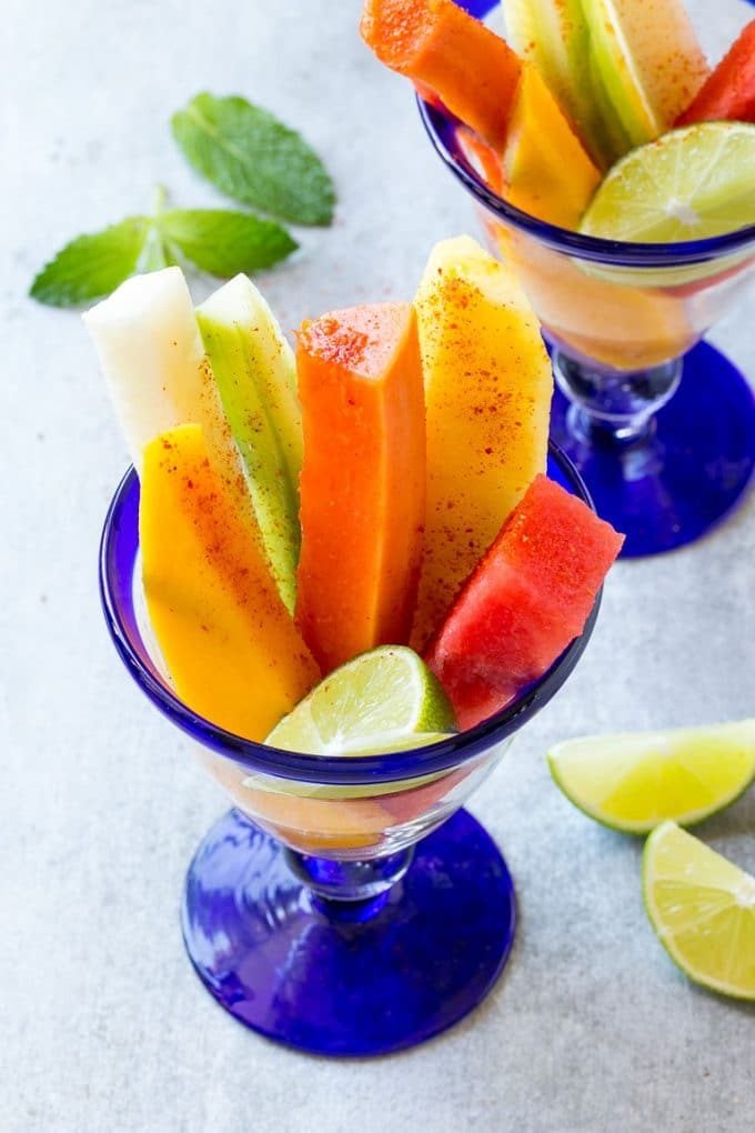 Mexican Fruit Cups | Fruit Cups | Mexican Fruit | Tropical Fruit #fruit #fruitcup #watermelon #pineapple #snack #healthy #fuyos Spears of colorful fresh fruit, cucumbers and jicama in Mexican fruit cups.