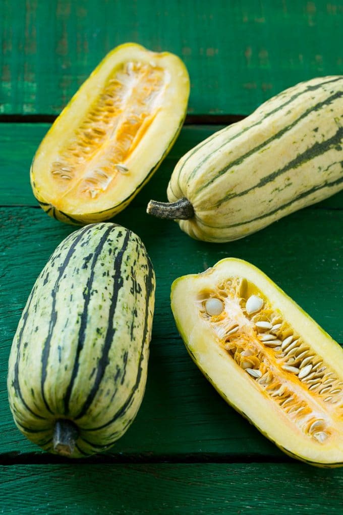 Brown Sugar Delicata Squash Recipe | Roasted Squash | Delicata Squash | Winter Squash Recipe #squash #wintersquash #brownsugar #sidedish #delicatasquash #dinner #fuyos Raw delicata squash on a green board.