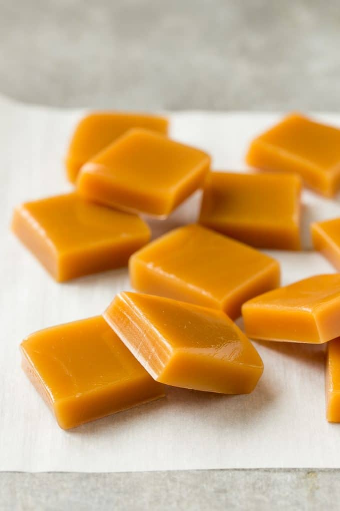 Microwave Caramels with Sea Salt Recipe | Homemade Caramels | Sea Salt Caramel | Homemade Candy #candy #caramels #caramel #microwavecaramels #homemade #dessert #fuyos Squares of cooked caramel on parchment.