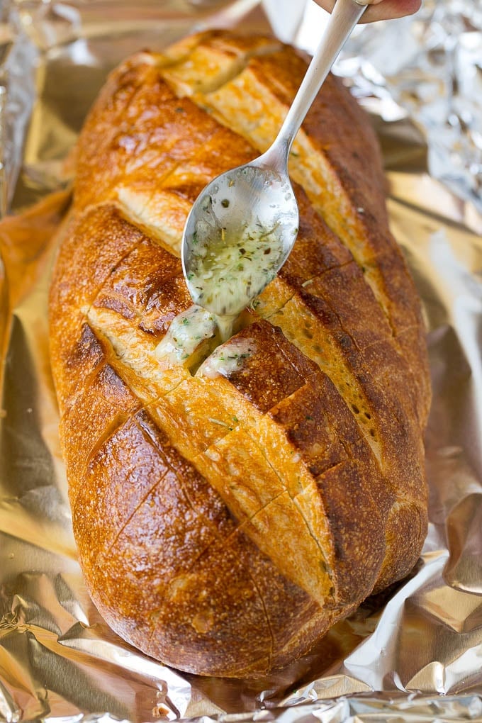 Pull Apart Bread | Garlic Bread | Cheese Bread #bread #garlic #cheese #sidedish #appetizer #fuyos A spoon drizzling garlic butter over a loaf of bread.