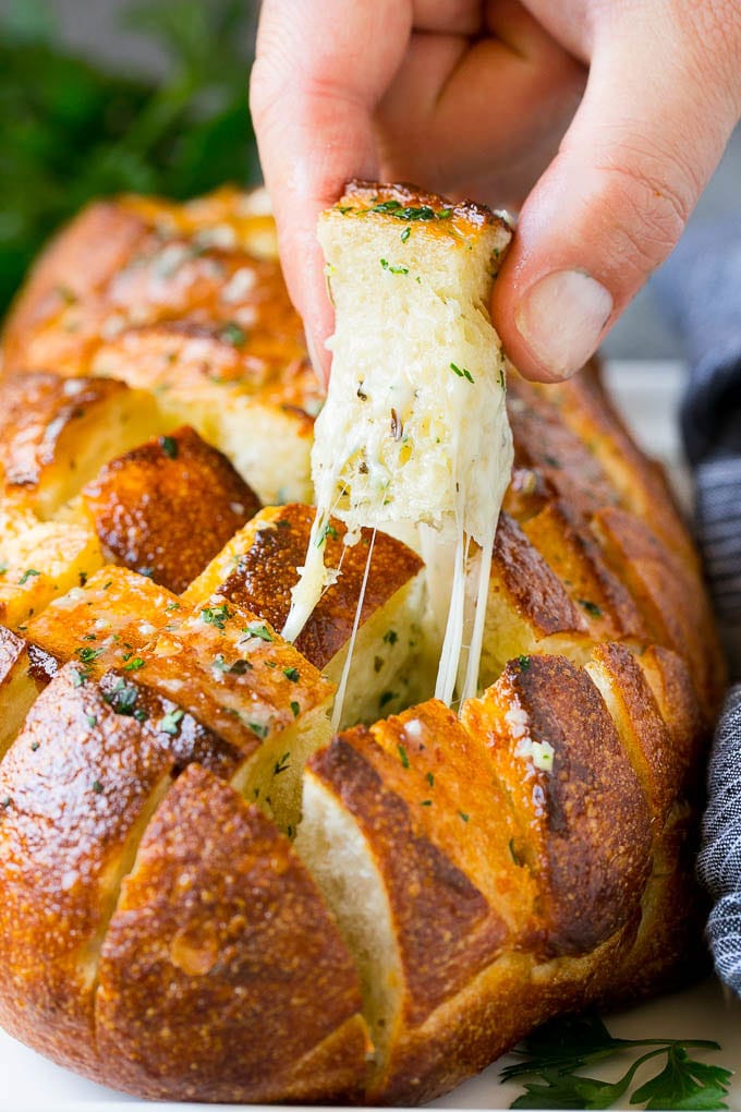 Pull Apart Bread | Garlic Bread | Cheese Bread #bread #garlic #cheese #sidedish #appetizer #fuyos A hand grabbing a piece of pull apart bread.
