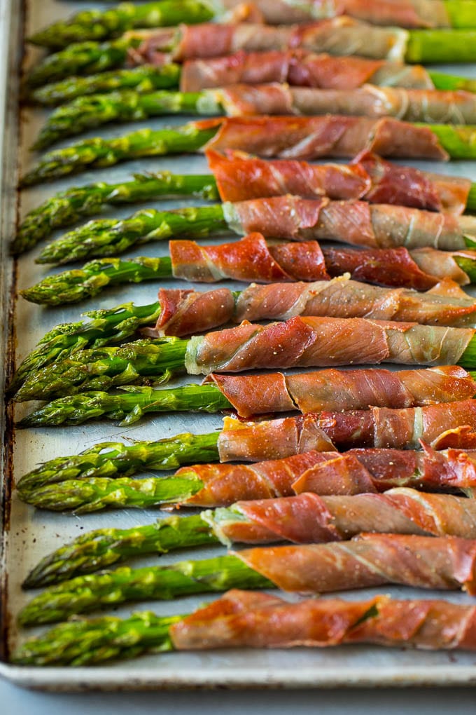 Prosciutto wrapped asparagus on a sheet pan.