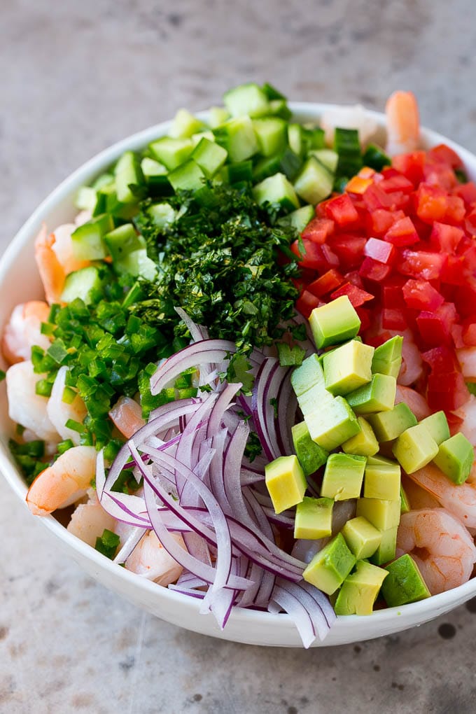 Shrimp Ceviche Recipe | Mexican Shrimp | Marinated Shrimp #shrimp #ceviche #cleaneating #healthy #lowcarb #keto #glutenfree #dinner #appetizer #fuyos Prawns, avocado, red onion tomatoes, cilantro, jalapeno and cilantro in a bowl.