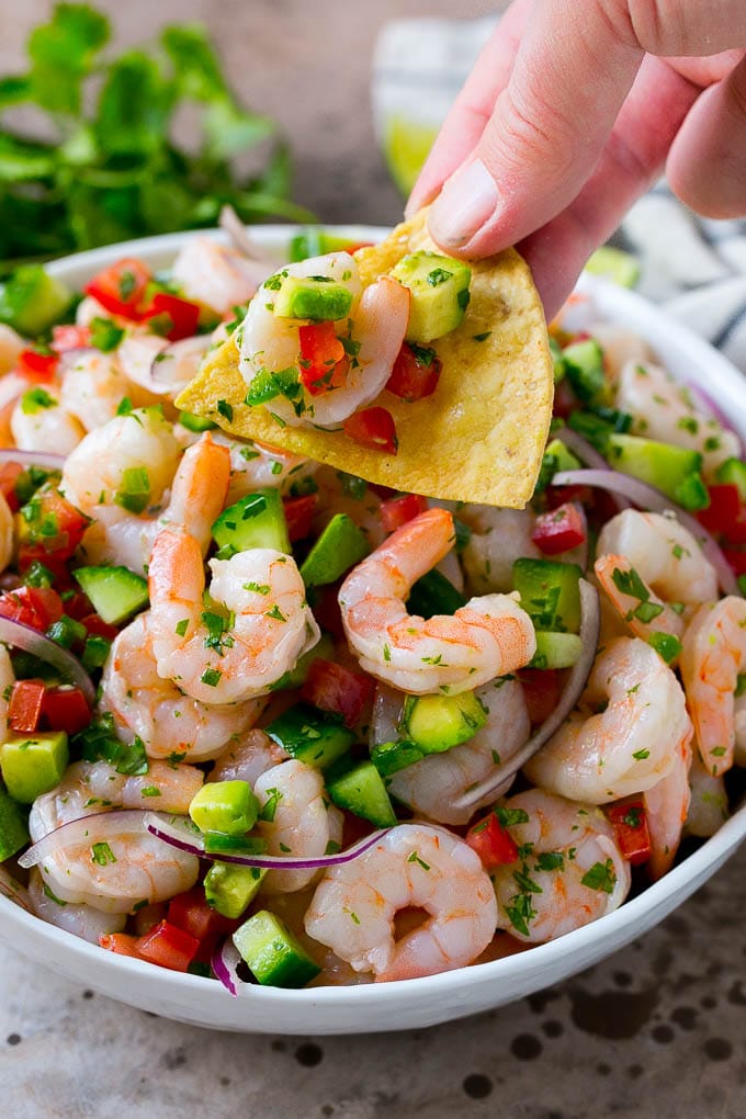 Shrimp Ceviche Recipe | Mexican Shrimp | Marinated Shrimp #shrimp #ceviche #cleaneating #healthy #lowcarb #keto #glutenfree #dinner #appetizer #fuyos A bowl of shrimp ceviche with a tortilla chip scooping some out.