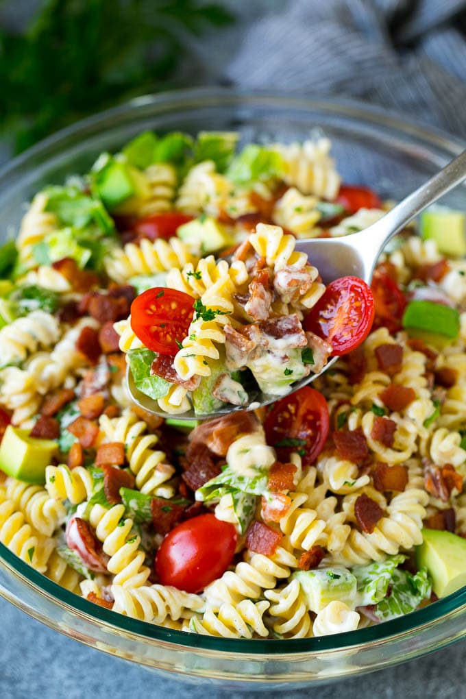BLT Pasta Salad Recipe | Easy Pasta Salad | Bacon Pasta Salad #salad #pasta #blt #bacon #avocado #dinner #fuyos A serving spoon filled with BLT pasta salad.