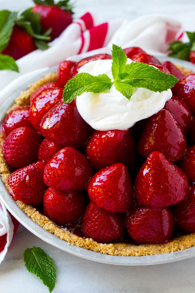 No Bake Strawberry Pie Recipe | Fresh Strawberry Pie | Strawberry Pie Recipe | No Bake Pie Recipe #strawberry #strawberrypie #nobake #nobakepie #dessert #fuyos Strawberry pie with a pile of strawberries inside a graham cracker crust, topped with glaze and whipped cream.