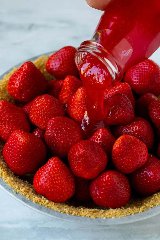 No Bake Strawberry Pie Recipe | Fresh Strawberry Pie | Strawberry Pie Recipe | No Bake Pie Recipe #strawberry #strawberrypie #nobake #nobakepie #dessert #fuyos Glaze being poured over a strawberry pie.