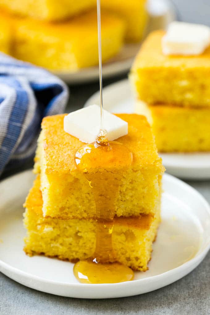 Honey Cornbread Recipe | Buttermilk Cornbread | Easy Cornbread | Homemade Cornbread | Cast Iron Cornbread #cornbread #honey #buttermilk #bread #fuyos A stack of cornbread topped with butter and honey