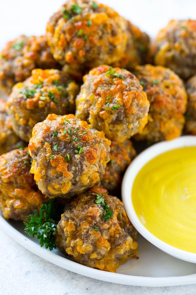 Sausage Cheese Balls Recipe | Sausage Balls Recipe | Bisquick Sausage Balls #sausage #sausageballs #balls #appetizer #cheeseballs #fuyos A pile of sausage cheese balls with a side of honey mustard.