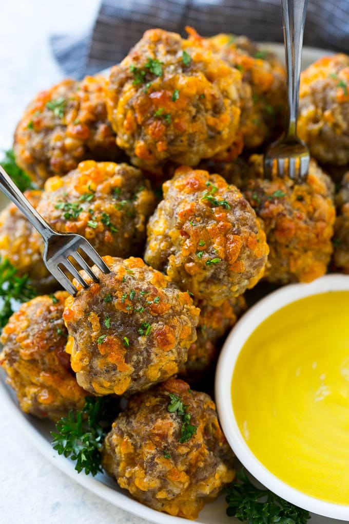 Sausage Cheese Balls Recipe | Sausage Balls Recipe | Bisquick Sausage Balls #sausage #sausageballs #balls #appetizer #cheeseballs #fuyos A plate of meatballs with cocktail forks.