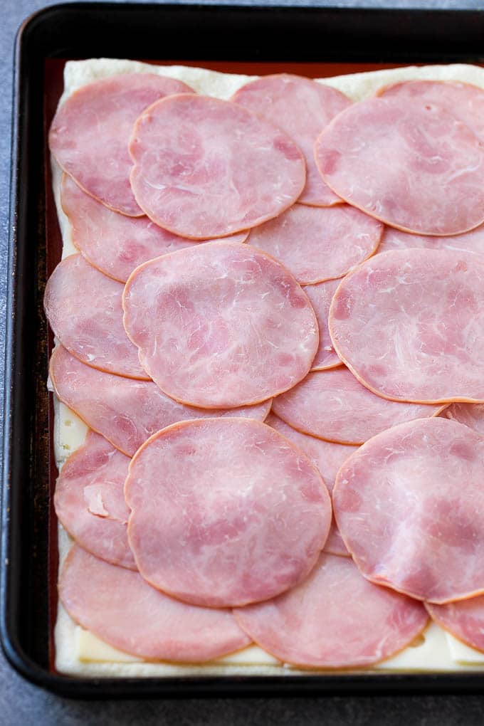 Ham and Cheese Pinwheels Recipe | Ham and Cheese Roll Ups | Ham and Cheese Rolls | Ham and Cheese Bread Rolls #ham #cheese #appetizer #pinwheels #fuyos Slices of ham and cheese on top of dough.