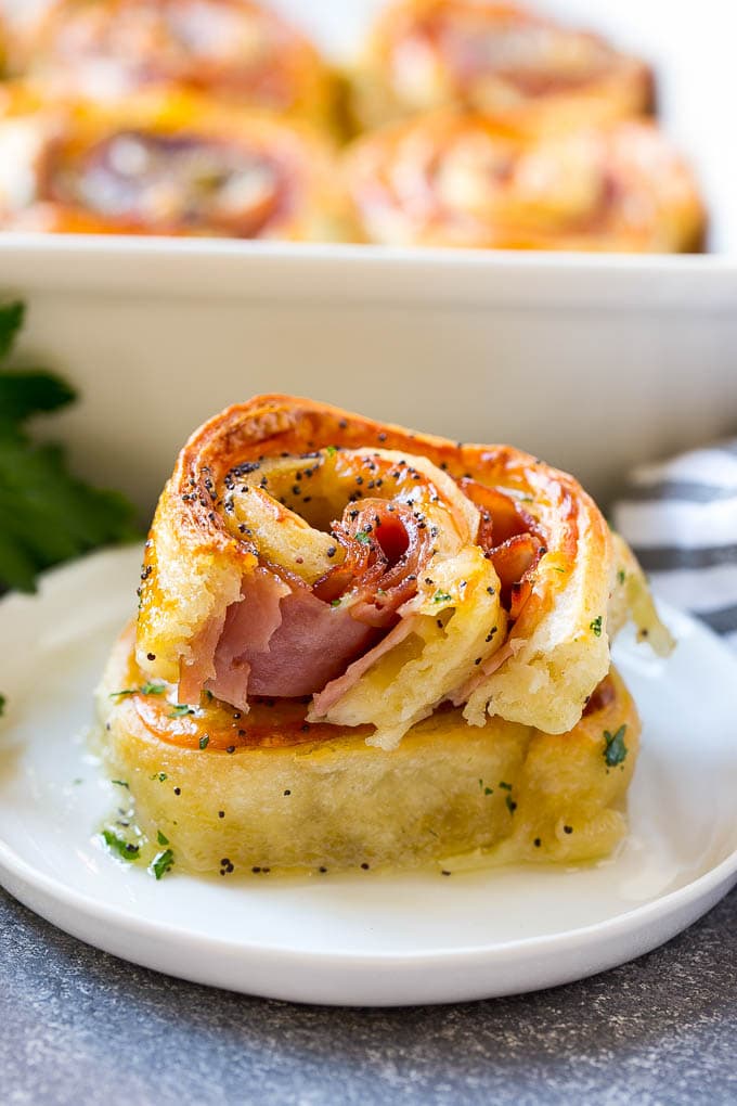 Ham and Cheese Pinwheels Recipe | Ham and Cheese Roll Ups | Ham and Cheese Rolls | Ham and Cheese Bread Rolls #ham #cheese #appetizer #pinwheels #fuyos Ham and cheese pinwheels stacked on a serving plate.