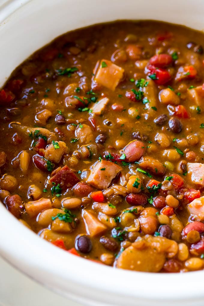 Slow Cooker Ham Bone Soup | Ham and Bean Soup | Ham Bone and Bean Soup | Ham Soup | Leftover Ham Recipe #ham #hamsoup #leftoverham #soup #slowcooker #crockpot #fuyos A slow cooker full of soup with parsley on top.