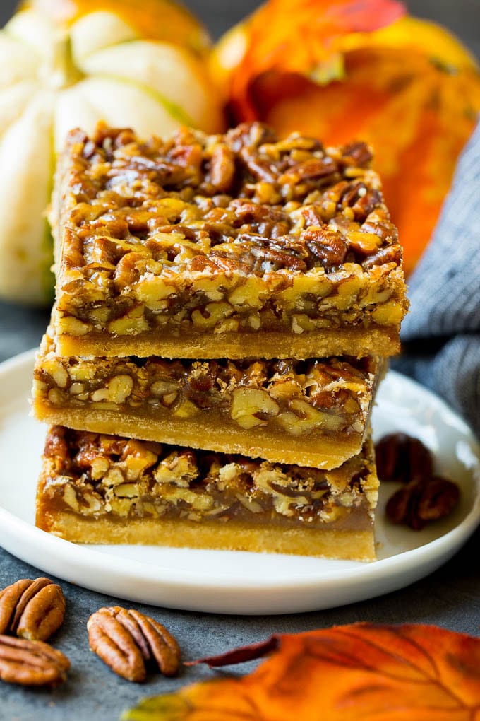 Pecan Pie Bars Recipe #pecans #pie #fall #pecanpie #dessert #thanksgiving #fuyos A stack of pecan pie bars on a plate.