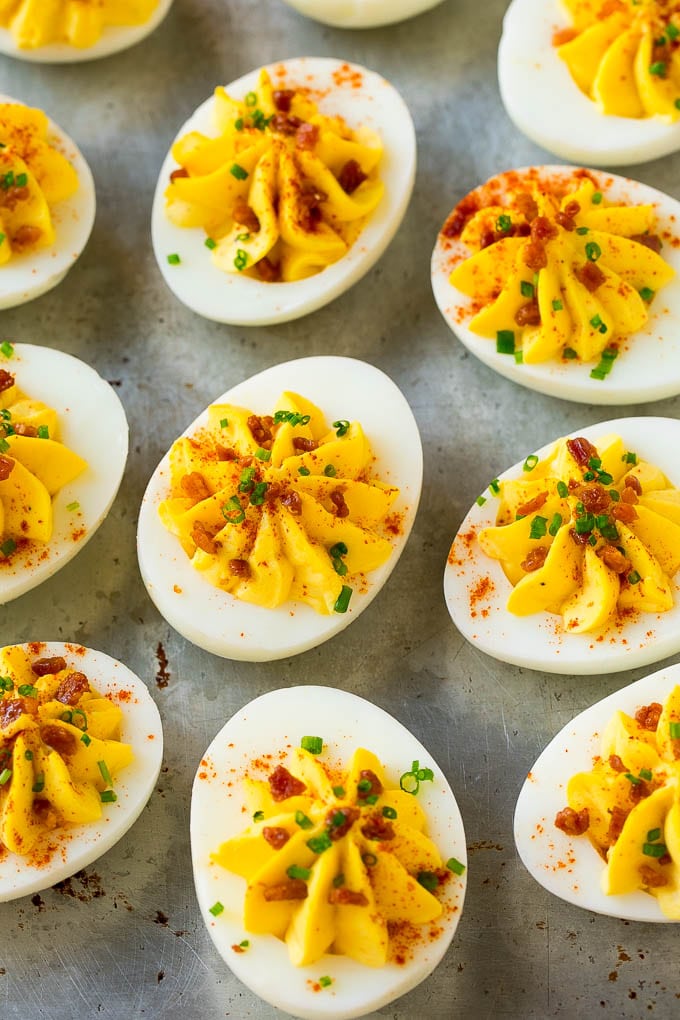 Bacon Deviled Eggs | Deviled Eggs Recipe #eggs #keto #lowcarb #bacon #appetizer #fuyos Bacon deviled eggs topped with chives and paprika on a sheet pan.