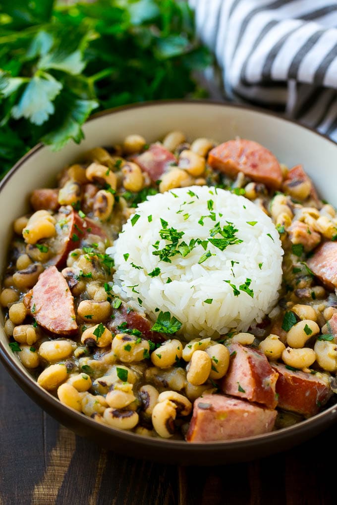 Slow Cooker Black Eyed Peas Recipe | Crock Pot Black Eyed Peas | Southern Black Eyed Peas | Black Eyed Peas with Ham | Black Eyed Peas with Sausage #blackeyedpeas #slowcooker #crockpot #sausage #newyears #dinner #fuyos A bowl of slow cooker black eyed peas with a scoop of rice.