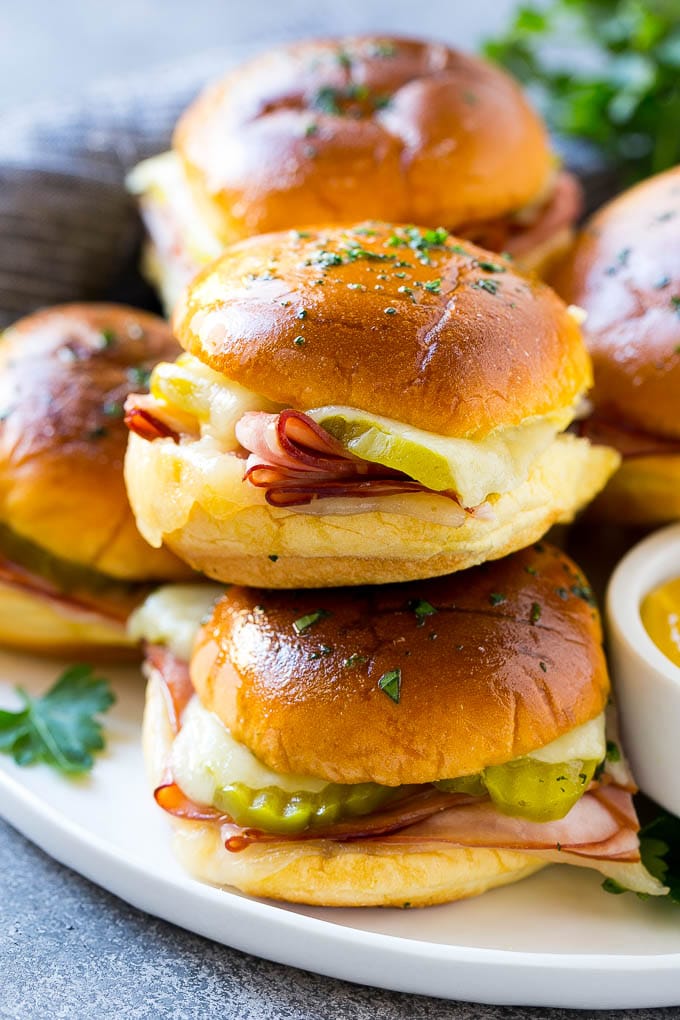 Cuban Sliders Recipe | Cuban Sandwich Recipe | Slider Sandwiches | Ham and Cheese Sliders #sliders #sandwiches #ham #cheese #appetizer #fuyos A pile of cuban sliders filled with ham, cheese and pickles.
