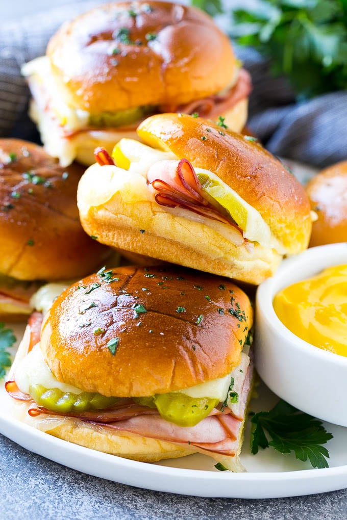Cuban Sliders Recipe | Cuban Sandwich Recipe | Slider Sandwiches | Ham and Cheese Sliders #sliders #sandwiches #ham #cheese #appetizer #fuyos A plate full of Cuban sliders with cheese, pickles and ham on buns.