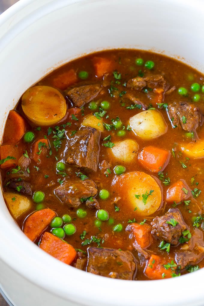 Slow Cooker Beef Stew Recipe | Beef and Potato Stew | Crock Pot Beef Stew | Easy Beef Stew #beef #beefstew #soup #slowcooker #crockpot #dinner #fuyos A slow cooker full of beef stew that contains meat, potatoes, carrots and peas, all in a savory broth.