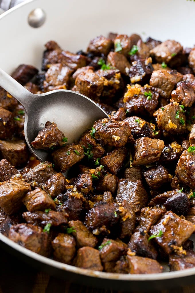Steak Bites in Garlic Butter Recipe | Garlic Steak | Sirloin Steak Recipe | Steak Appetizer #steak #lowcarb #keto #fuyos #dinner A pan of steak bites with a serving spoon.
