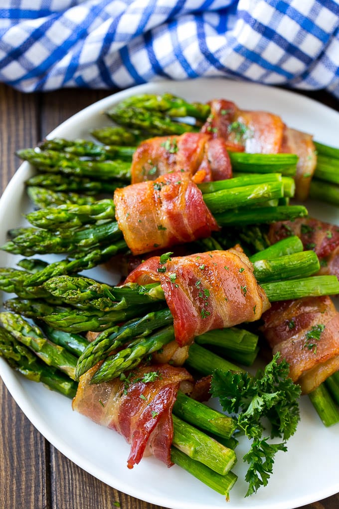 A plate of bacon wrapped asparagus bundles garnished with parsley.