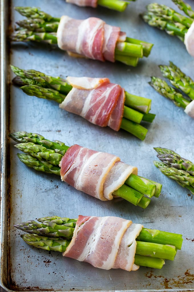 Raw asparagus bundles on a sheet pan.