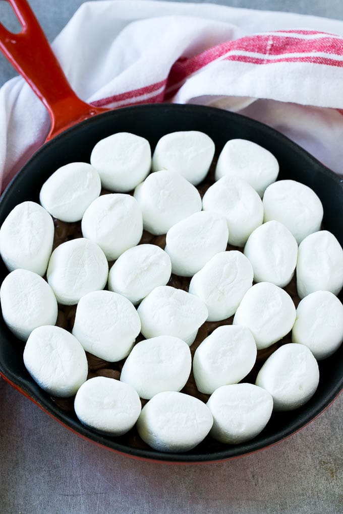 S'mores Dip Recipe | S'mores Skillet | Baked S'mores #smores #dip #chocolate #marshmallow #dessert #fuyos A pan of chocolate chips topped with whole marshmallows.