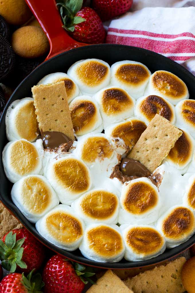 S'mores Dip Recipe | S'mores Skillet | Baked S'mores #smores #dip #chocolate #marshmallow #dessert #fuyos A skillet of s'mores dip with melted milk chocolate topped with toasted marshmallows.