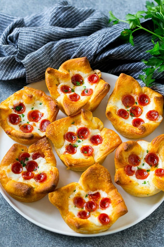 Pizza Muffins Recipe | Pizza Bites | Pizza Cups | Pizza Appetizer #pizza #appetizer #fuyos Pizza muffins on a serving plate garnished with parsley.