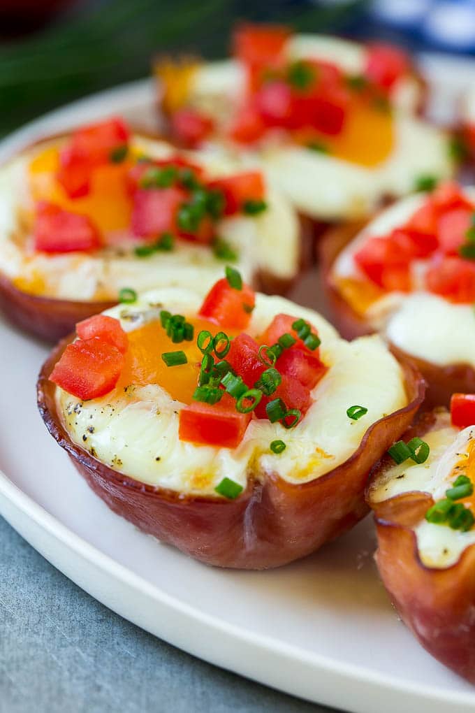 Ham and Egg Cups Recipe | Low Carb Breakfast | Ham and Eggs #ham #eggs #lowcarb #breakfast #fuyos A plate of ham and egg cups topped with diced tomatoes and chives.