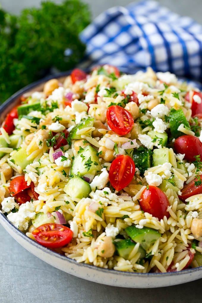 Orzo Salad Recipe | Orzo Pasta Salad | Greek Orzo Salad | Mediterranean Orzo Salad #pastasalad #orzo #greekfood #salad #fuyos Orzo salad in a serving bowl with tomatoes, cucumbers and chickpeas.