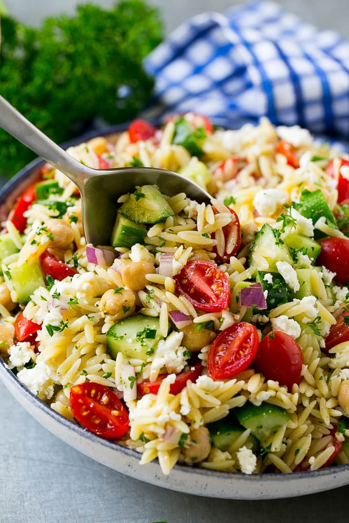 Orzo Salad Recipe | Orzo Pasta Salad | Greek Orzo Salad | Mediterranean Orzo Salad #pastasalad #orzo #greekfood #salad #fuyos Orzo pasta salad with a serving spoon in the bowl.