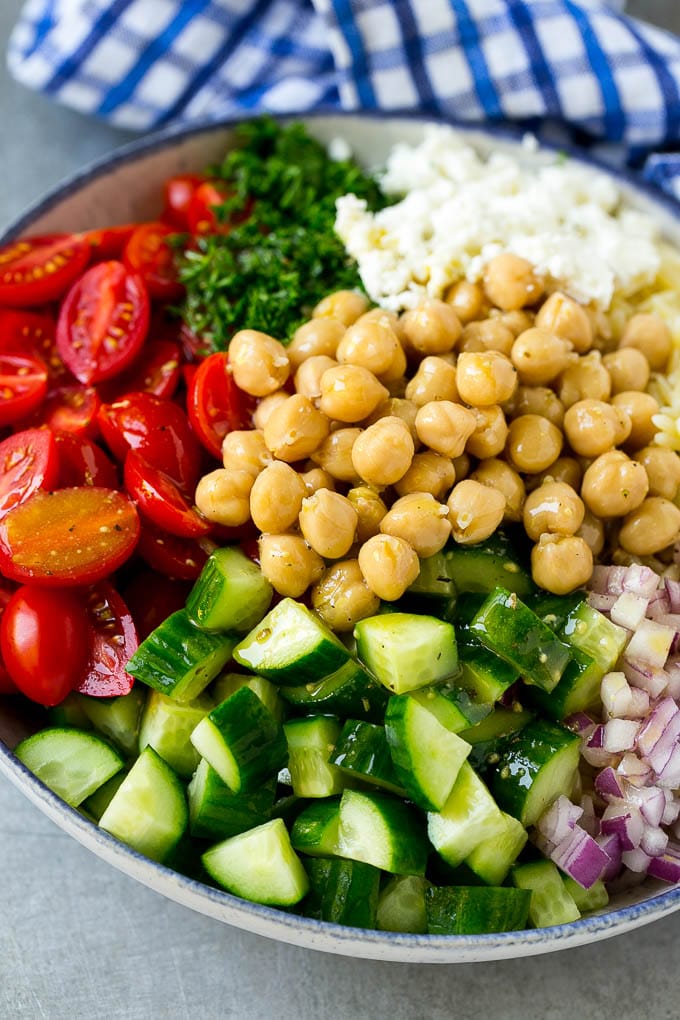 Orzo Salad Recipe | Orzo Pasta Salad | Greek Orzo Salad | Mediterranean Orzo Salad #pastasalad #orzo #greekfood #salad #fuyos A bowl of orzo pasta, tomatoes, cucumbers, red onions, chickpeas and feta cheese topped with dressing.