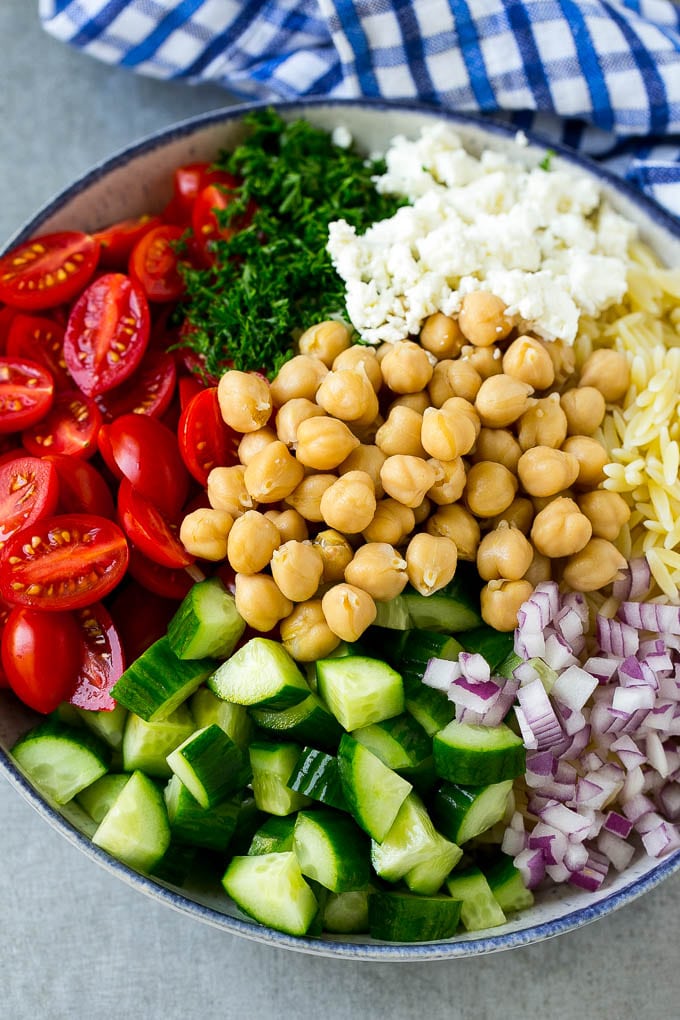Orzo Salad Recipe | Orzo Pasta Salad | Greek Orzo Salad | Mediterranean Orzo Salad #pastasalad #orzo #greekfood #salad #fuyos A bowl of orzo pasta, cucumbers, cherry tomatoes, feta cheese, red onions, herbs and chickpeas.
