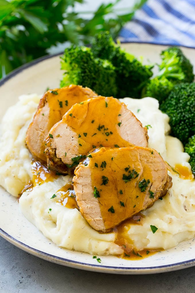 Slow Cooker Pork Tenderloin Recipe | Crock Pot Pork Tenderloin | Easy Pork Tenderloin #slowcooker #crockpot #pork #dinner #fuyos Sliced slow cooker pork tenderloin served over mashed potatoes with broccoli.