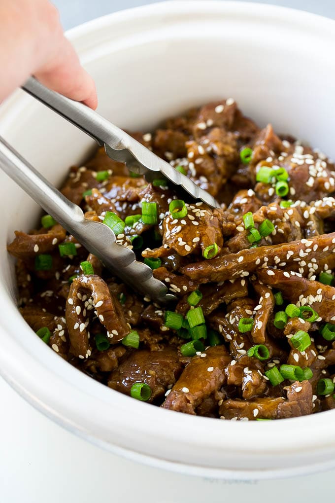 Slow Cooker Korean Beef Recipe | Korean Beef | Flank Steak Recipe #dinner #beef #slowcooker #crockpot #asian #fuyos A crock pot of Korean beef with serving tongs in it.