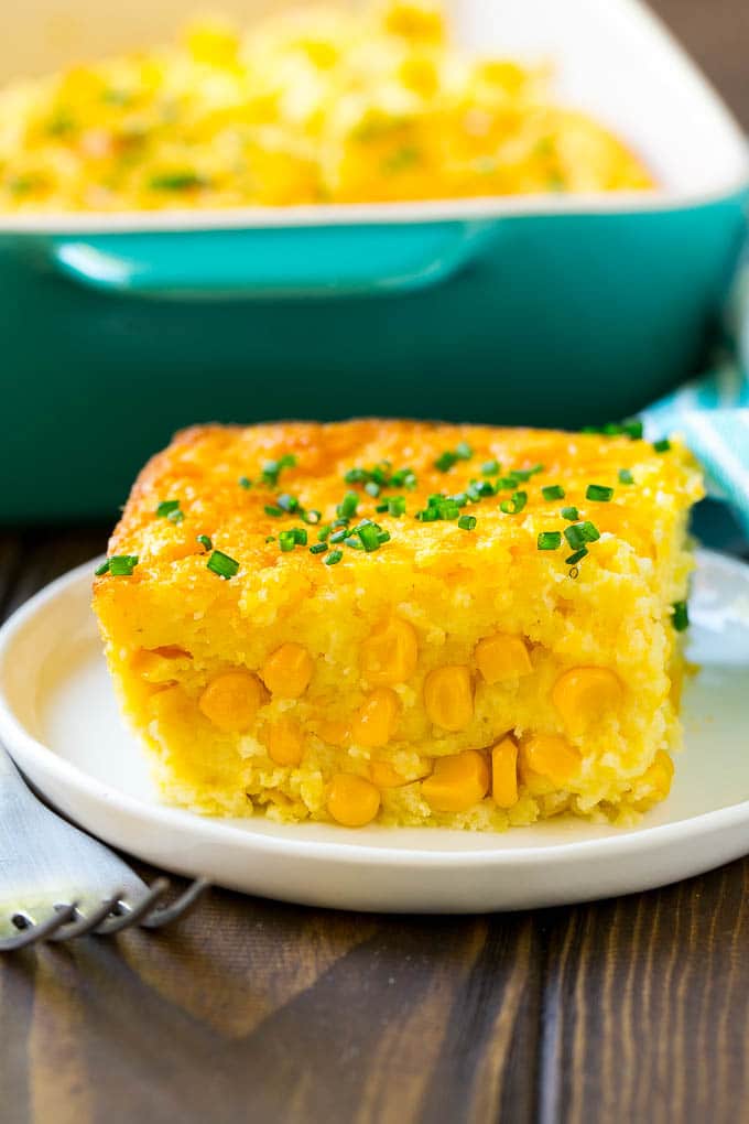 Corn Pudding Recipe | Corn Casserole | Corn Side Dish #corn #pudding #casserole #sidedish #thanksgiving #dinner #fuyos A serving of corn pudding on a plate, garnished with chives.