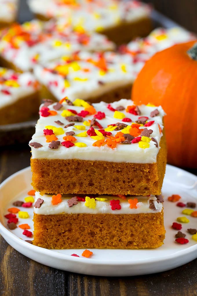 Pumpkin Bars Recipe | Pumpkin Cake | Pumpkin Dessert #pumpkin #fall #dessert #fuyos #thanksgiving A stack of pumpkin bars topped with frosting and sprinkles.