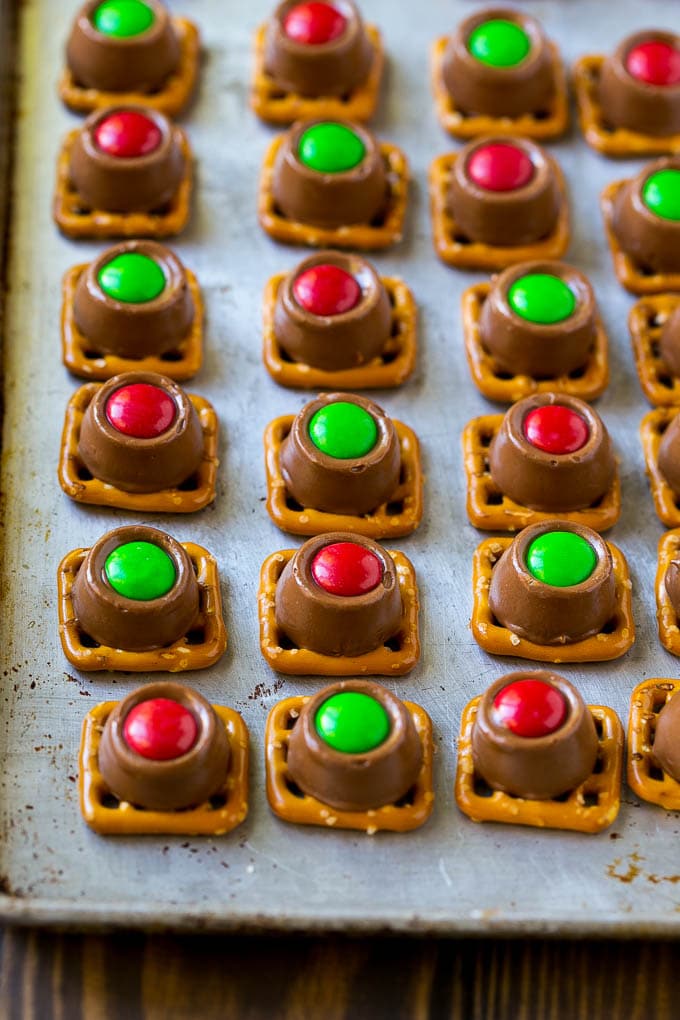Rolo Pretzels Recipe | Chocolate Pretzels | Caramel Pretzels | Holiday Candy #christmas #baking #dessert #candy #chocolate #caramel #pretzels #fuyos Treats with red and green M&M's pressed on top all on a baking sheet.
