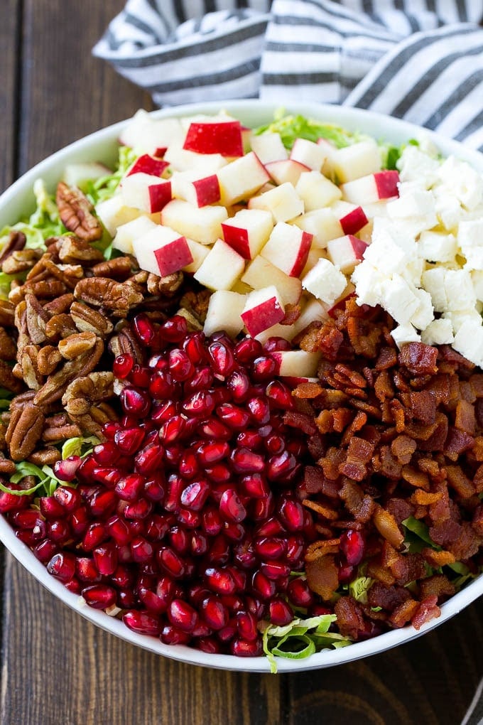 Shredded brussels sprouts topped with pomegranate seeds, bacon, feta cheese and apples.