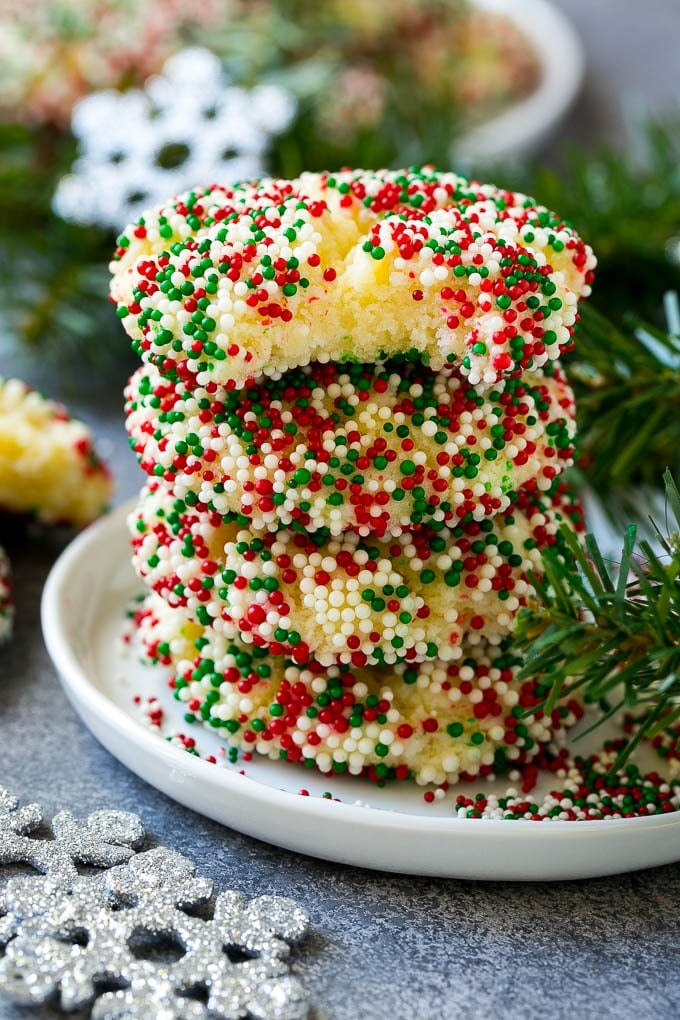 Gooey Butter Cookies Recipe | Cake Mix Cookies | Sprinkle Cookies | Christmas Cookies #cookies #butter #sprinkles #christmas #dessert #baking #fuyos A stack of gooey butter cookies with a bite taken out of one.